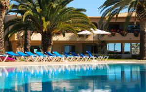 a group of chairs and palm trees next to a swimming pool at Apartamentos Turisticos Vila Palmeira in Lagos