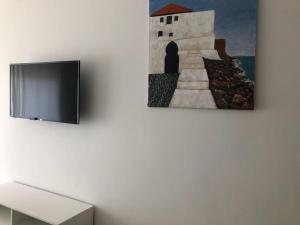 a tv on a wall with a painting of a person at Marina Golf Appart Chez Hicham in Asilah
