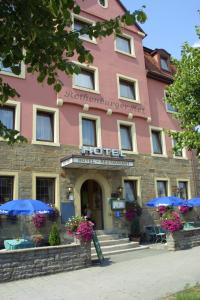 een roze hotel met blauwe parasols ervoor bij Hotel Rothenburger Hof in Rothenburg ob der Tauber