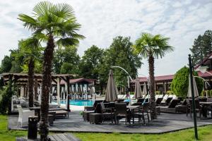 a resort with a pool and chairs and palm trees at Hotel Snagov Club in Snagov