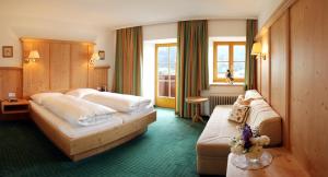 テルフェス・イム・シュトゥーバイにあるLandgut Thalerhofのベッド2台とソファが備わるホテルルームです。