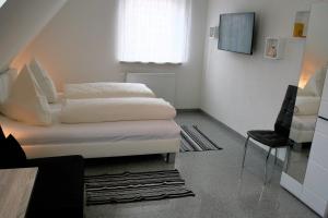 a small bedroom with two beds and a chair at Haus zum Schlosspark in Veitshöchheim