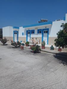 a white building with blue doors and potted plants at Matina Studios in Kefalos