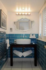 Baño de azulejos azules con lavabo y espejo en Corner House Bed & Breakfast, en West Runton