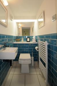 Baño de azulejos azules con aseo y lavamanos en Corner House Bed & Breakfast, en West Runton