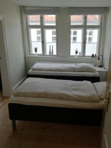 Ribe Sønderport Bed & Kitchen في ريبي: سريرين في غرفة بها نافذتين