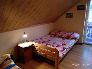 a small bedroom with a bed with pink sheets at Domki u Strażaka obiekt Całoroczny in Solina