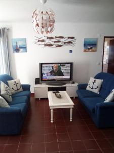 a living room with two blue couches and a tv at Casa Das Ondas - Praia Do Norte in Nazaré