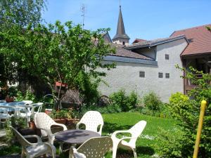a patio with white chairs and tables and a church at Auberge d'Anthy in Anthy