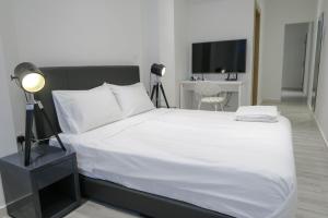 a bedroom with a white bed and a television at Comfy Studio 5 by ReCharge in Singapore