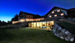a large house with a stone wall at night at Hotel Auf der Gsteig GmbH in Lechbruck
