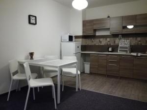 a kitchen with a white table and white chairs at Apartmán Prefa in Benešov nad Ploučnicí