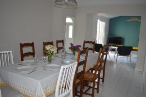 einen Esstisch mit einem weißen Tischtuch und Stühlen in der Unterkunft Gite de la Foye - La Couleur des prés in Combrand