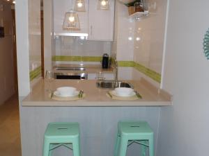 una cucina con lavandino e 2 sgabelli verdi di Estudio HC a Málaga
