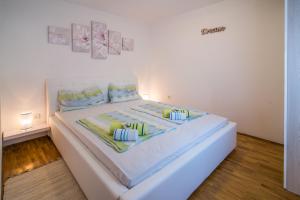a bedroom with a white bed with blue and green pillows at Apartments Braut Krk in Krk
