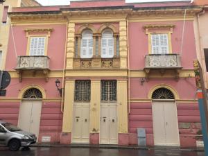 un edificio rosa con ventanas blancas y puertas en una calle en Appartamento Casa Tonina en Carloforte