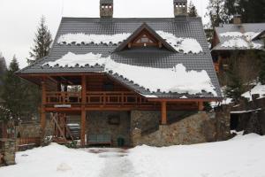 Cabaña de madera con nieve en el techo en Na Gori, en Slavske