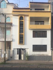 une maison blanche et jaune avec une clôture dans l'établissement Ap Palmarejo, à Praia