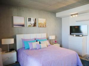 a bedroom with a purple bed with a flat screen tv at Family Studio Aveiro in Aveiro