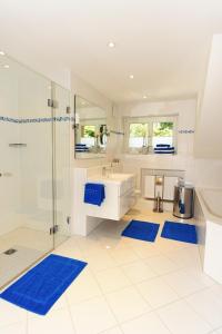 uma casa de banho com um lavatório, um chuveiro e tapetes azuis em Ferienwohnung Am Kurpark -Wohnung 3,150qm- mit Lift em Garmisch-Partenkirchen