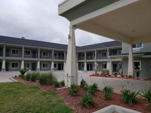 una vista exterior de un gran edificio con un patio en Scottish Inns & Suites - Crosby, en Crosby