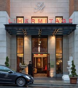 a man is walking down the street in front of a store at L'Hermitage Hotel in Vancouver