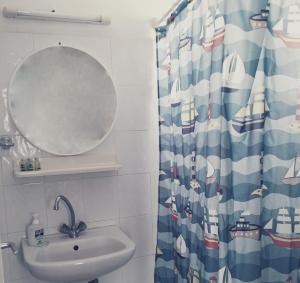 y baño con lavabo, espejo y cortina de ducha. en Romanza, en Cherronisos