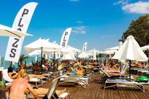 a crowd of people sitting on chairs and umbrellas at a beach at Amulett Wellness Apartman in Siófok