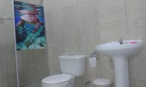 a bathroom with a toilet and a sink and a painting at Pousadinha Mangabeiras Familia e Grupos in Guriri