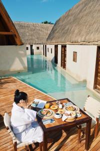 a woman sitting at a table in front of a pool at Hotel Boutique Punta Caliza - Adults Oriented in Holbox Island
