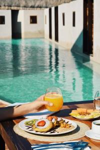 a table with a plate of food and a glass of orange juice at Hotel Boutique Punta Caliza - Adults Oriented in Holbox Island