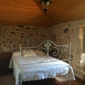 uma cama de metal num quarto com uma parede de pedra em Refugio dos Cregos em Riba de Mouro