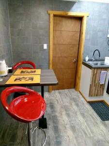 cocina con silla roja, mesa y fregadero en El Pionero, en Coyhaique