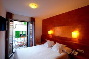 ロザスにあるHotel Carmenのベッドとバルコニー付きのホテルルーム