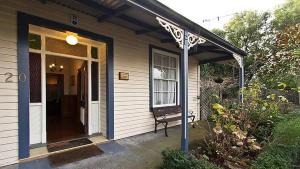 um alpendre de uma casa com um banco em Brockworth Cottage em Christchurch