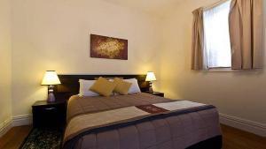 a bedroom with a bed with two lamps and a window at Brockworth Cottage in Christchurch
