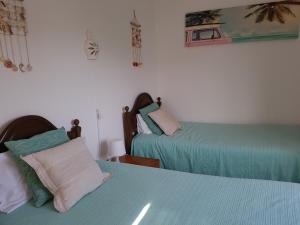 two beds in a room with green and pink at Casa Barroca in Carrapateira