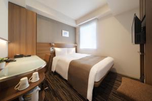 a hotel room with two beds and a television at Keio Presso Inn Hamamatsucho in Tokyo
