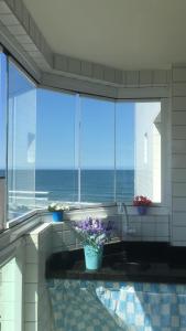 a kitchen with a view of the ocean through windows at Residencial Viamar in Praia Grande