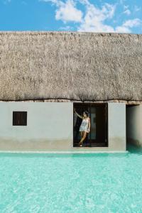 a woman standing in the doorway of a thatched house at Hotel Boutique Punta Caliza - Adults Oriented in Holbox Island