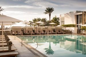 a pool at a hotel with chairs and umbrellas at Nobu Hotel Miami Beach in Miami Beach
