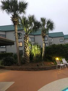 a resort with palm trees and chairs and a building at Gulf Shores Plantation in Gulf Shores