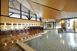 a large room with a pool with chairs in it at Kurobe Kanko Hotel in Omachi