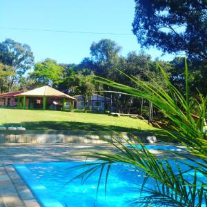 a swimming pool in a yard with a house in the background at Pousada Villa das Águas,chalés com Ar condicionado e um rio no quintal in Monte Alegre do Sul