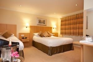 a hotel room with two beds and a desk at Lingwood Lodge in Bowness-on-Windermere +10 photos