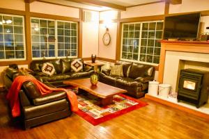 a living room with leather furniture and a fireplace at Altitude Madarao in Iiyama