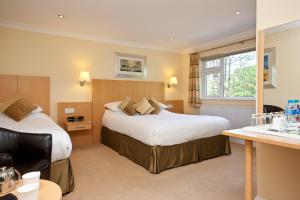 a hotel room with two beds and a desk at Lingwood Lodge in Bowness-on-Windermere