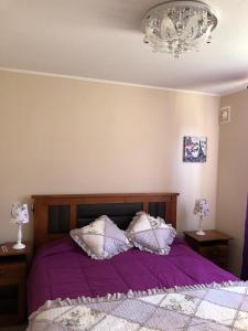 una camera da letto con un letto viola con cuscini e un lampadario di Departamento Libertad a La Serena