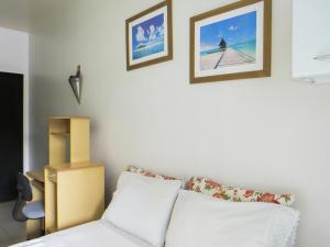 a bedroom with a white bed and two pictures on the wall at Amanda Suites in Manaus