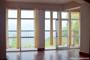 an empty room with large windows with a view at Hotel Aashiyana in Kalimpong